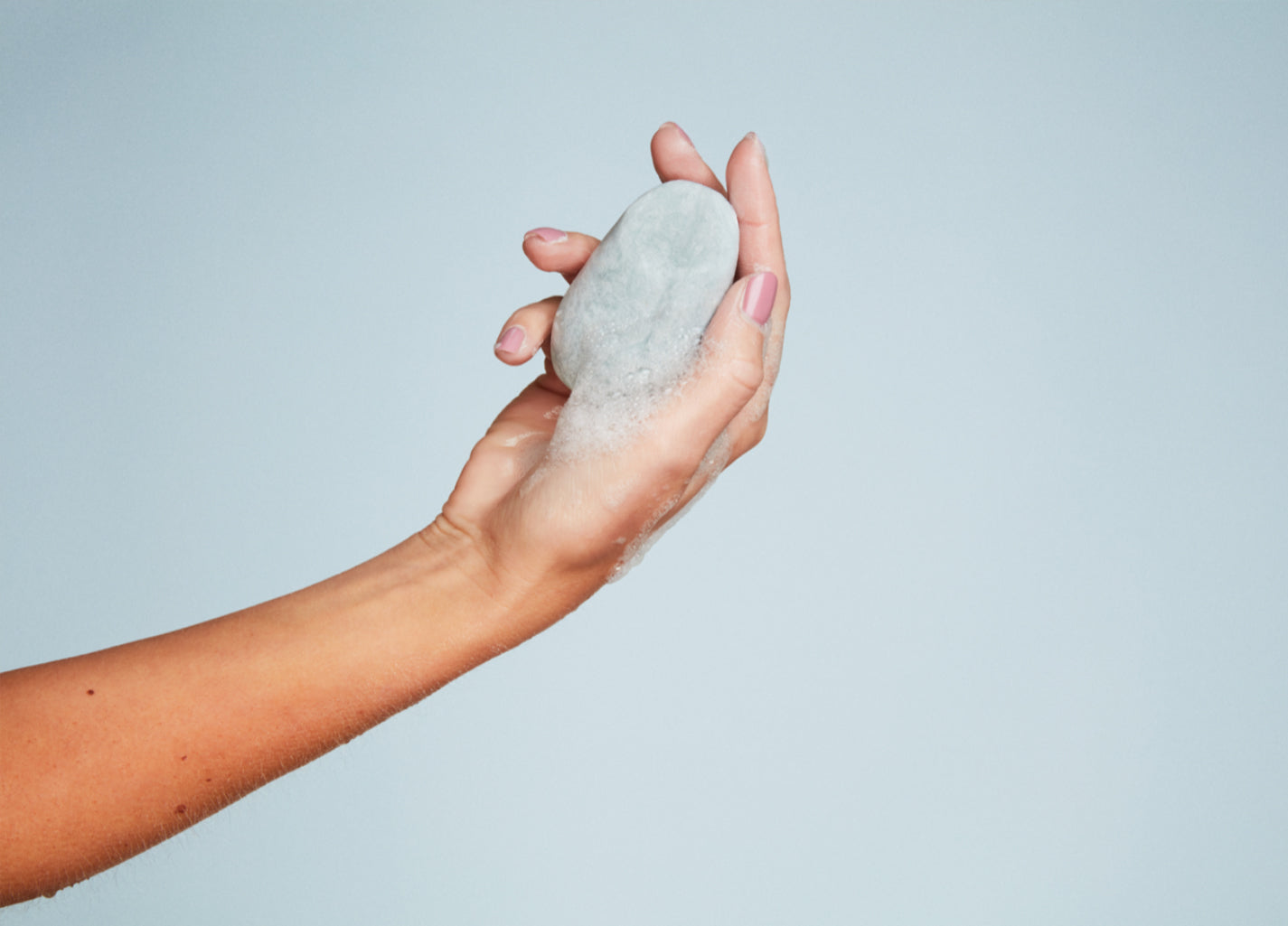 Person holding a bar in their hands to show the size of the shampoo bar