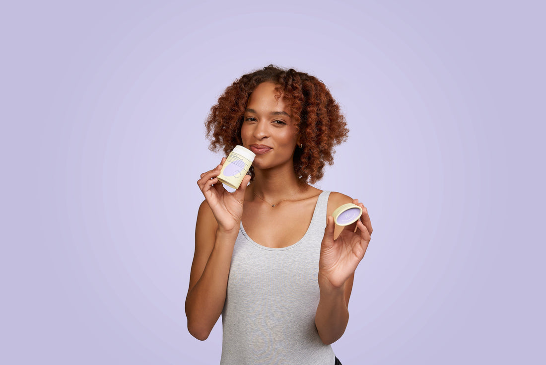 A female model smelling a deodorant bar on a violet background.