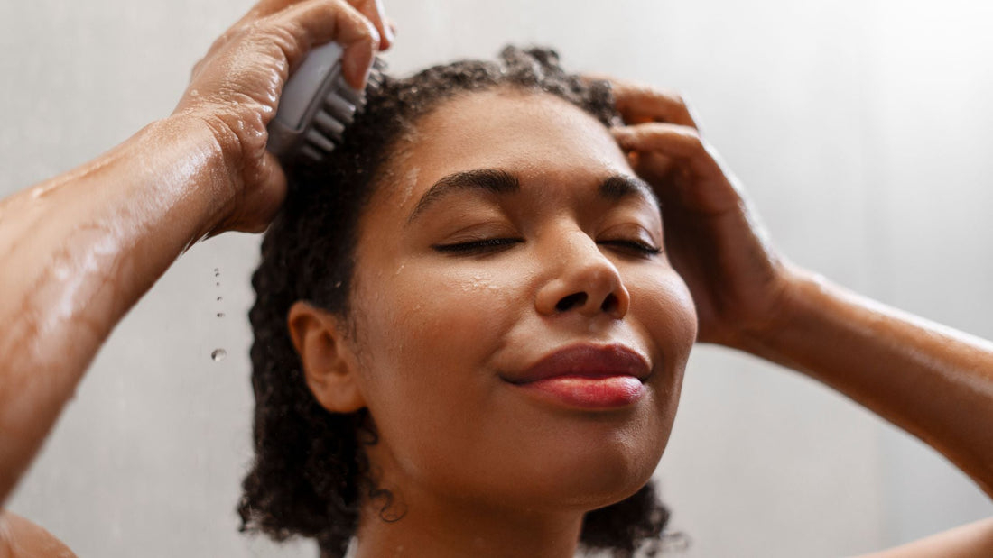 Woman washing dark curly hair in the shower.