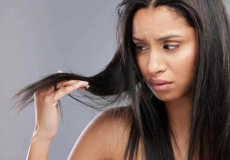 A dark haired woman looking at dry hair.