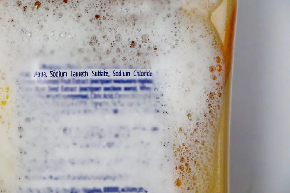 Orange shampoo bottle with ingredients shown.