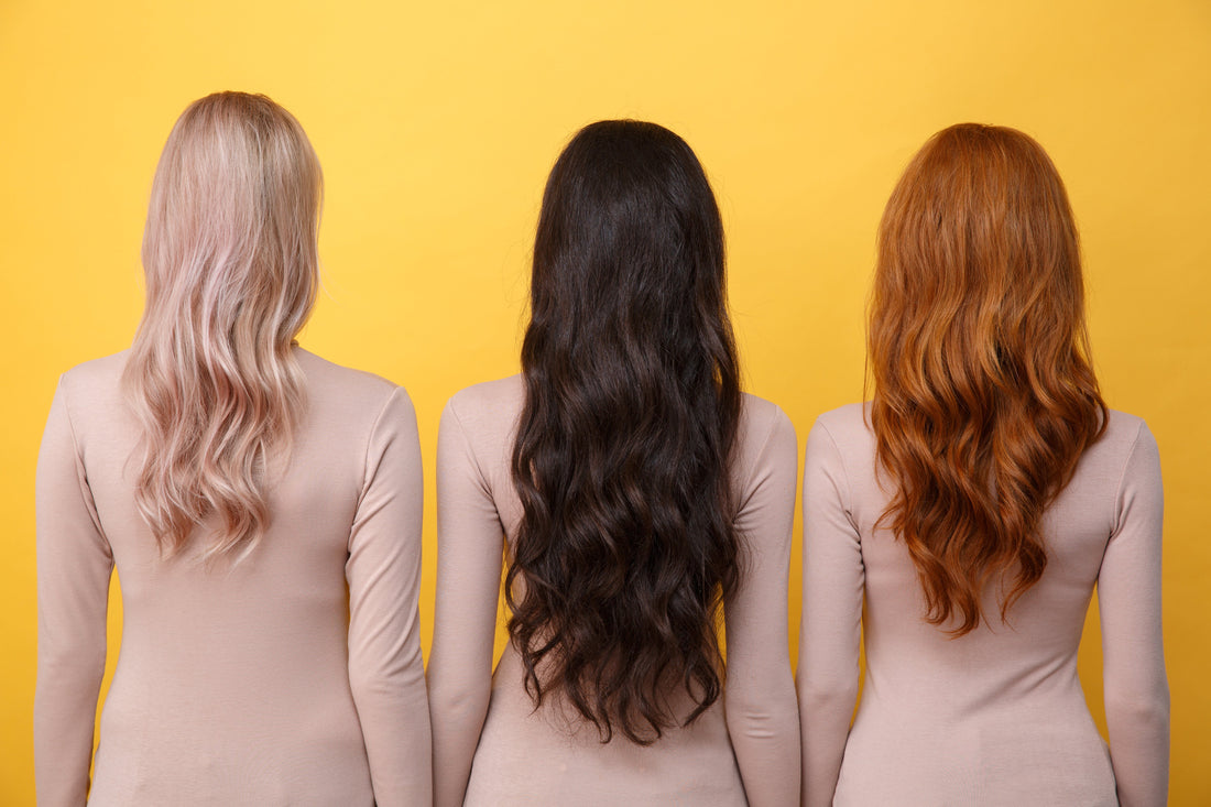 Three female models with different hair types facing a yellow wall.