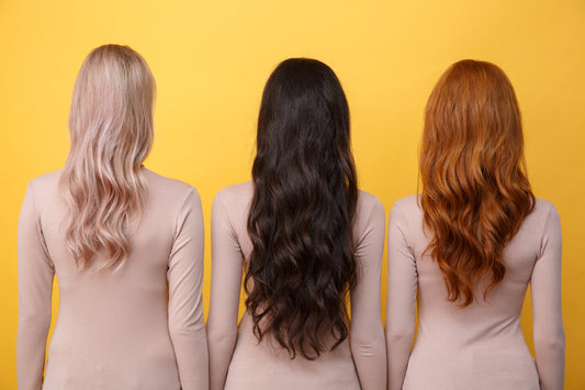 Three female models with different hair types facing a yellow wall.