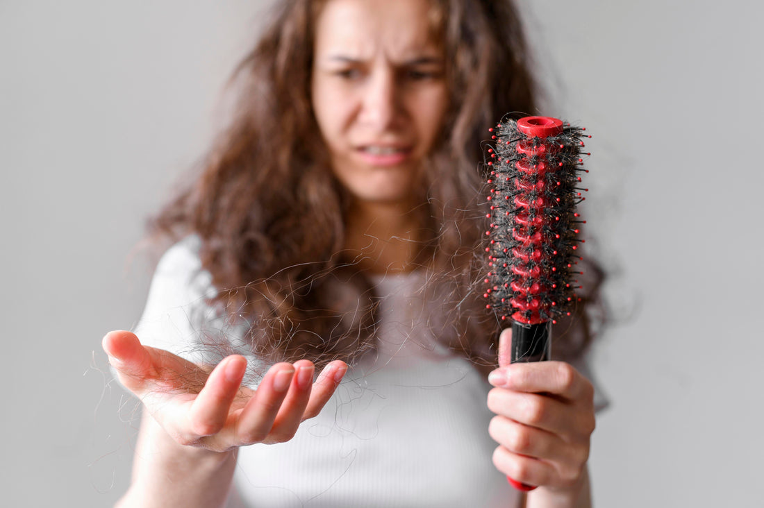 Woman holding a hair brush looking at dry hair.