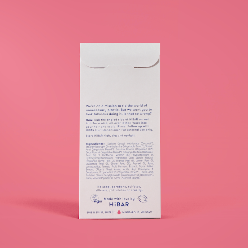 Photo of the back of the packaging of the shampoo bar on a red background.