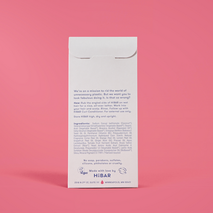 Photo of the back of the packaging of the shampoo bar on a red background.