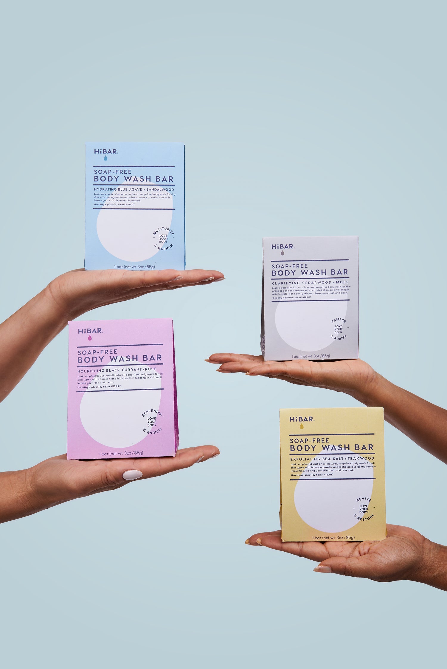 Two women holding up four boxes of body wash bars on a light blue background.